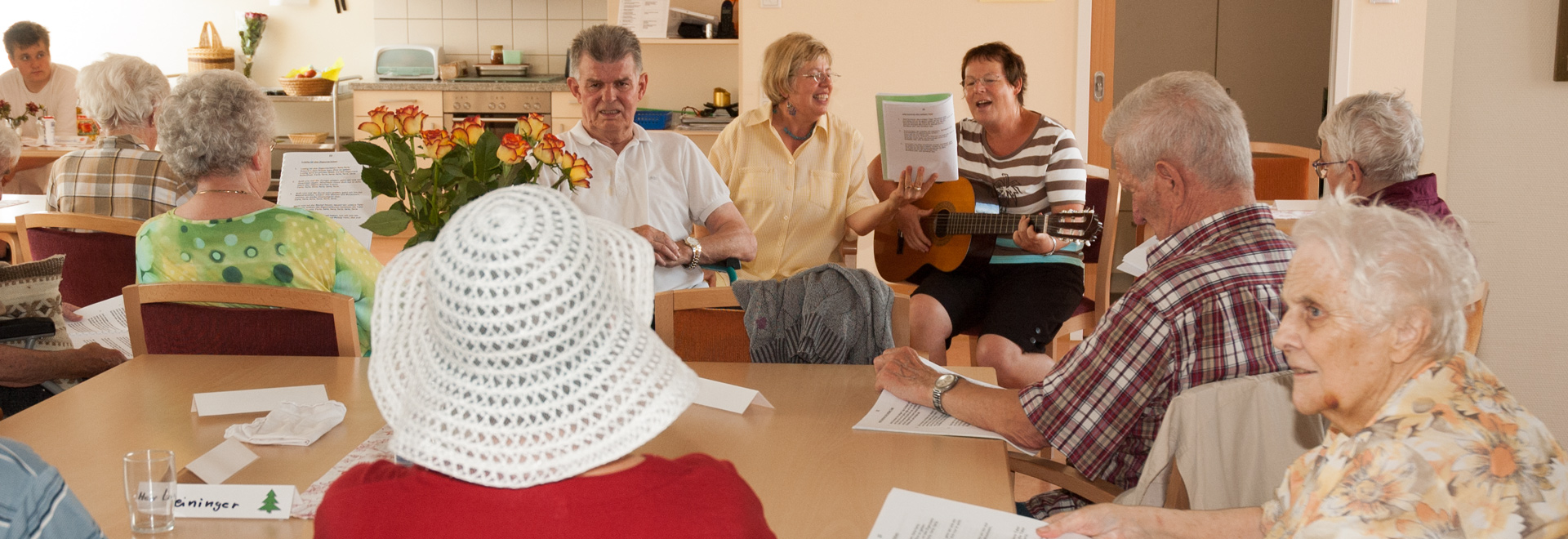 Senioren sitzen an einem Tisch und singen