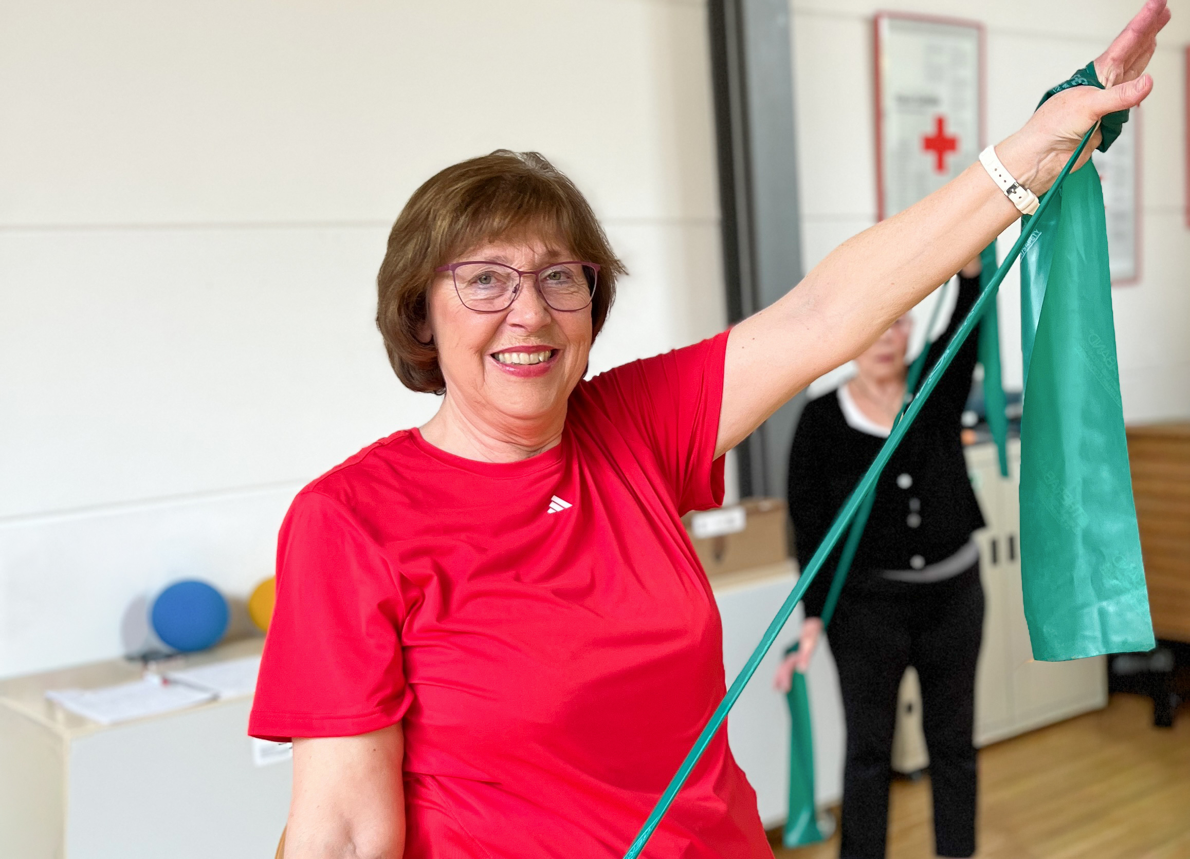 Das Bild zeigt Übungsleiterin Karin Luthner in einer Bewegungsstunde.rogrammes mit Frau Karin Luthner im roten T-Shirt.