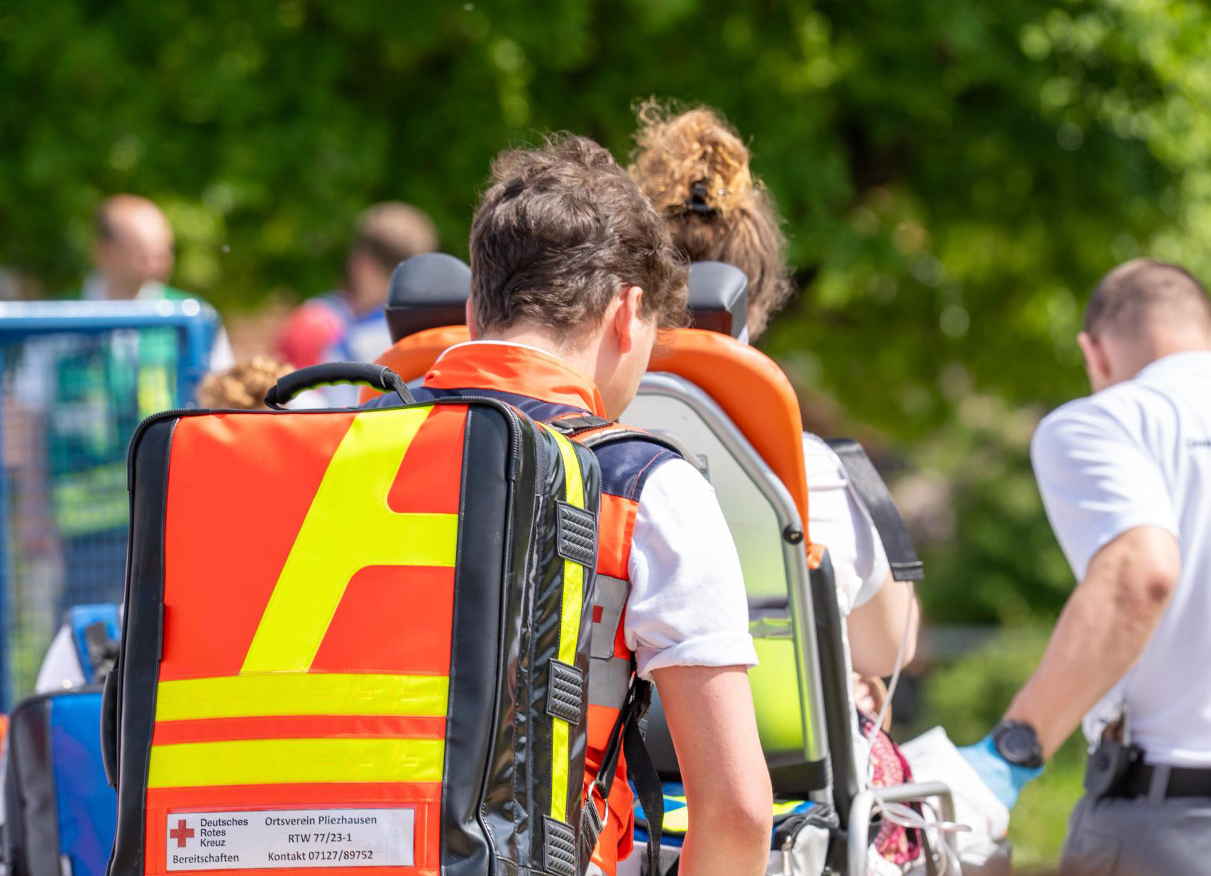 Das Bild zeigt Einsatzkräfte bei der Versorgung einer verletzten Person. ransport einer Verletzten auf einer Trageiner wiese vor dem Veranstaltungsort Gelände der neuen Wacherz im Interview mit dem SWR Fernsehen