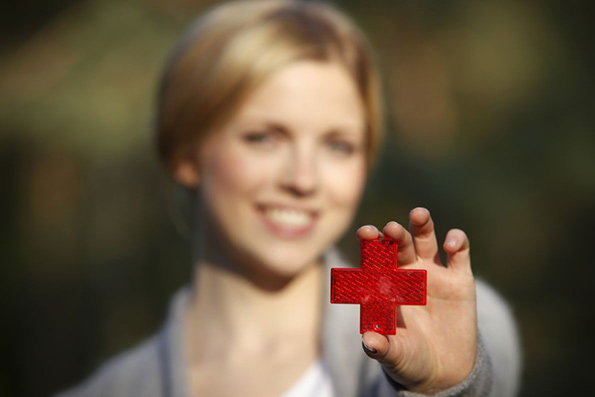 Frau zeigt ein rotes Kreuz